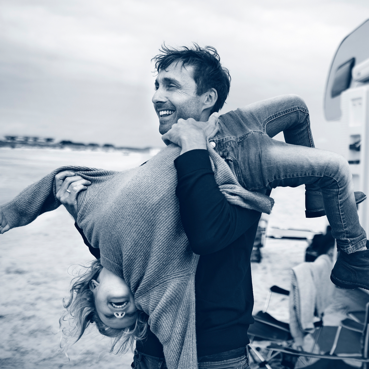 Man holding child upside down on the beach