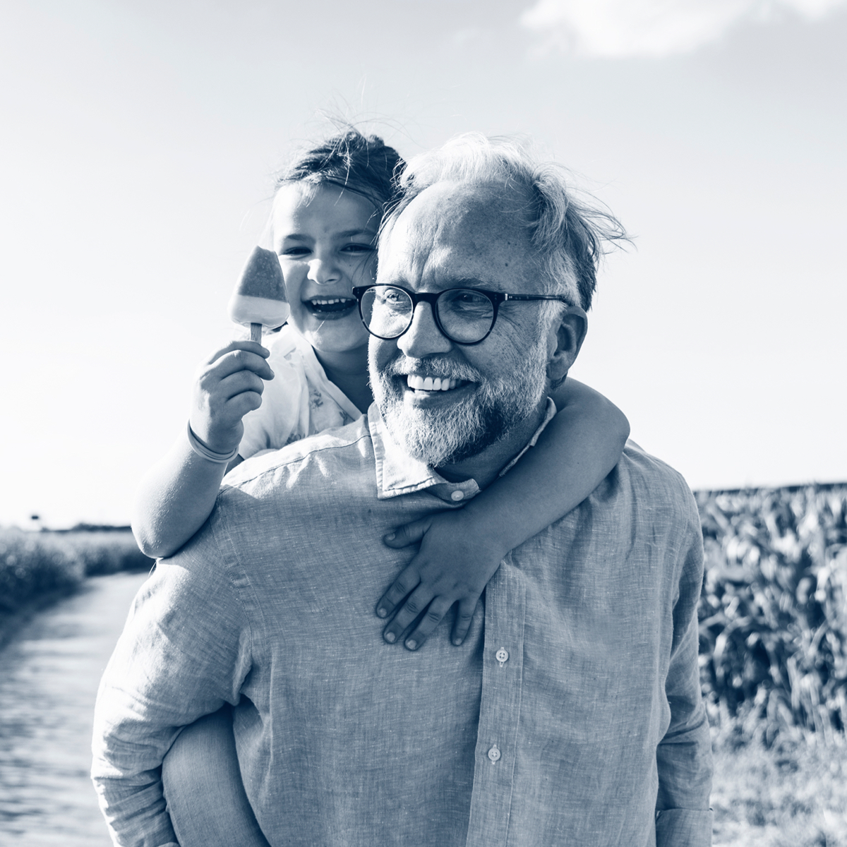 Grandchild on grandfather's shoulders eating an ice lolly