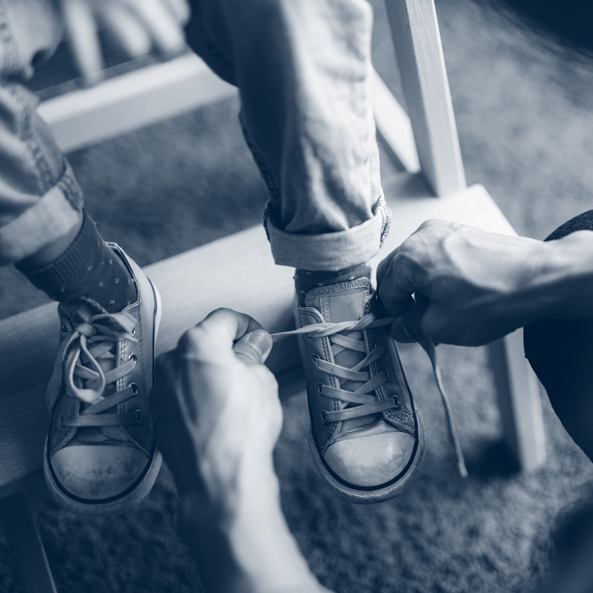 An adult ties a child's shoe laces