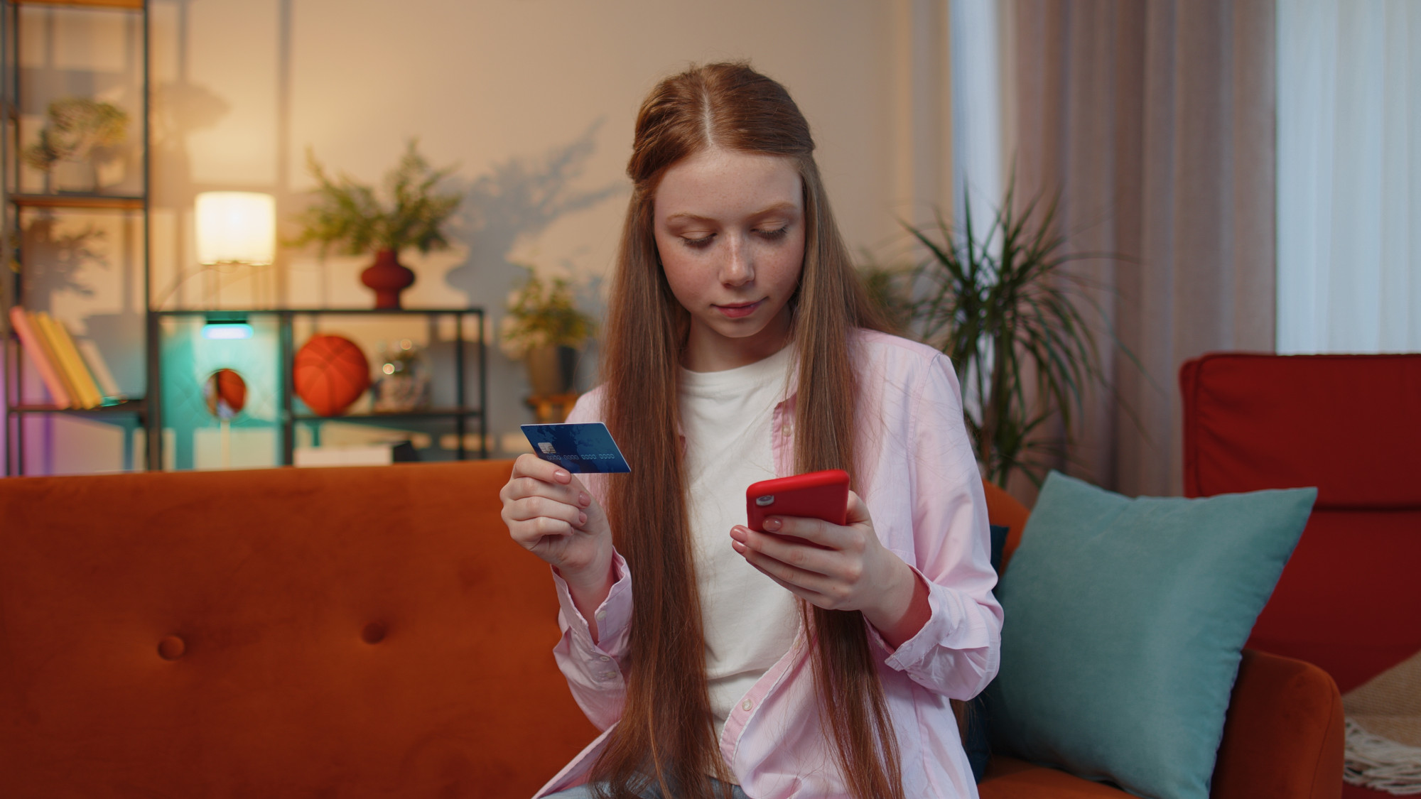 Why it's so important to talk about money with your children. Here, a teenage girl uses a credit card to make a purchase on her phone.